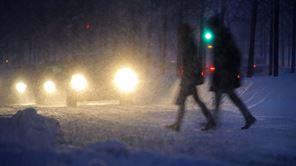 Bilar och människor på en snöig gata